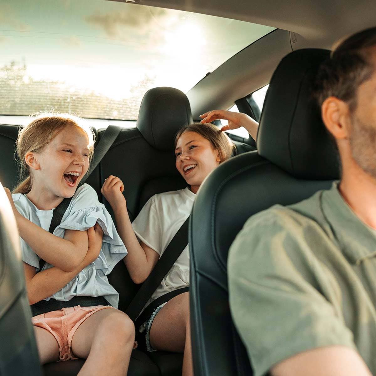 Två glada barn i baksätet på en bil