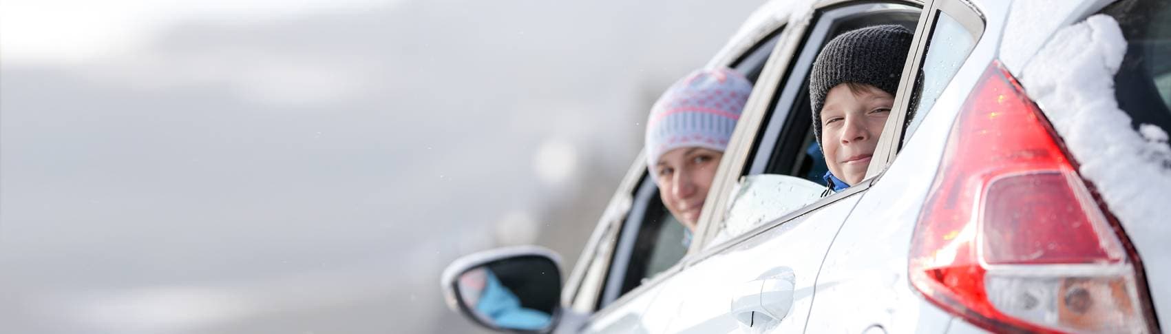 Två personer tittar ut från fönster från en bil.