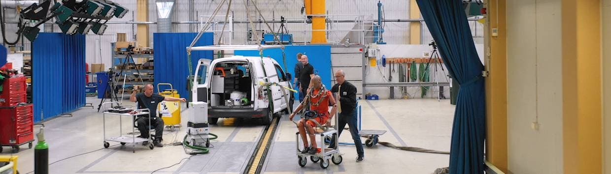 fyra män i en verkstad förbereder för krocktest med skåpbil