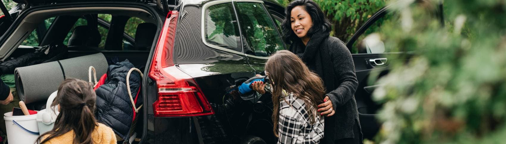 En kvinna och ett barn kopplar in en laddningskabel till sin elbil