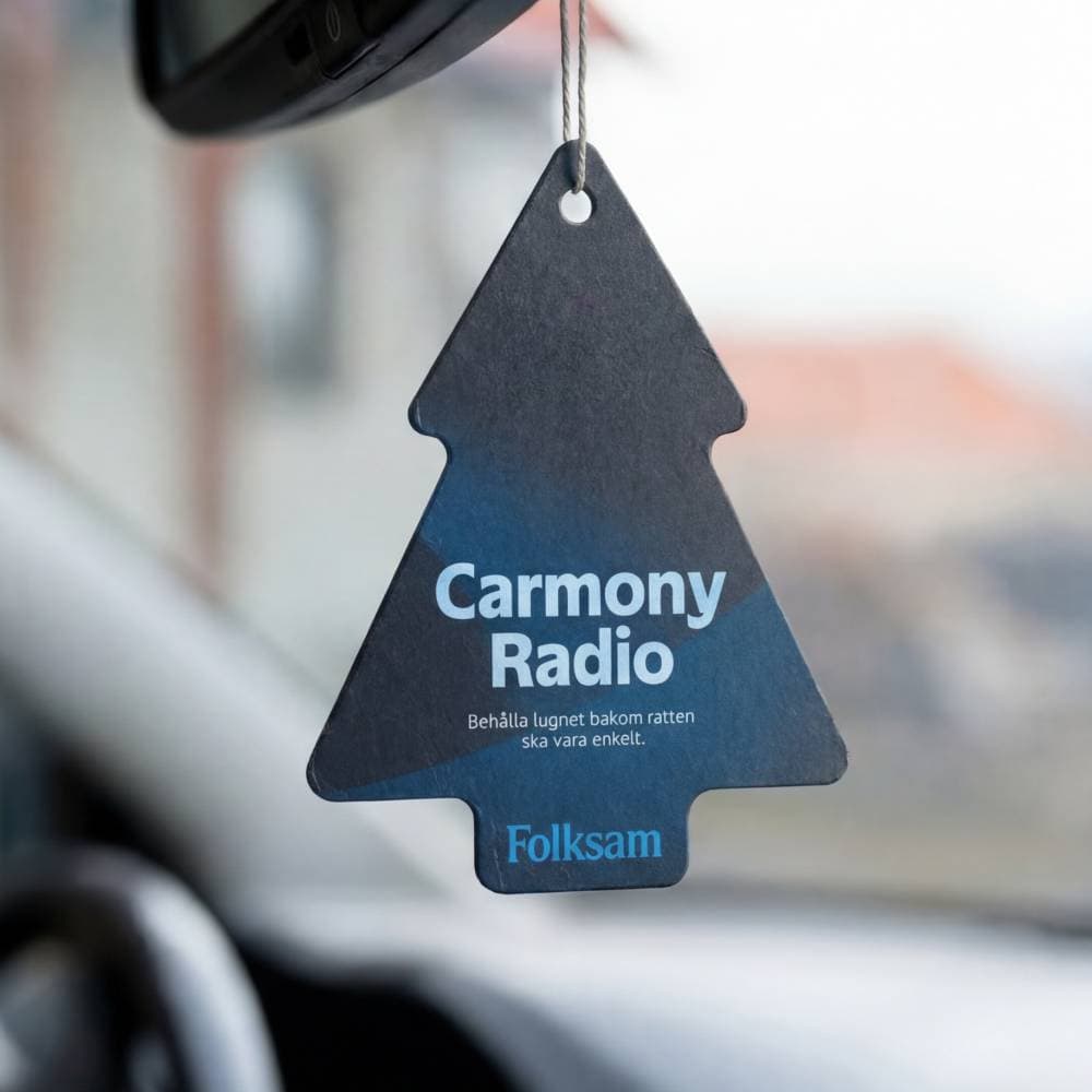 En doftgran med texten Carmony Radio hänger på backspegeln i en bil.