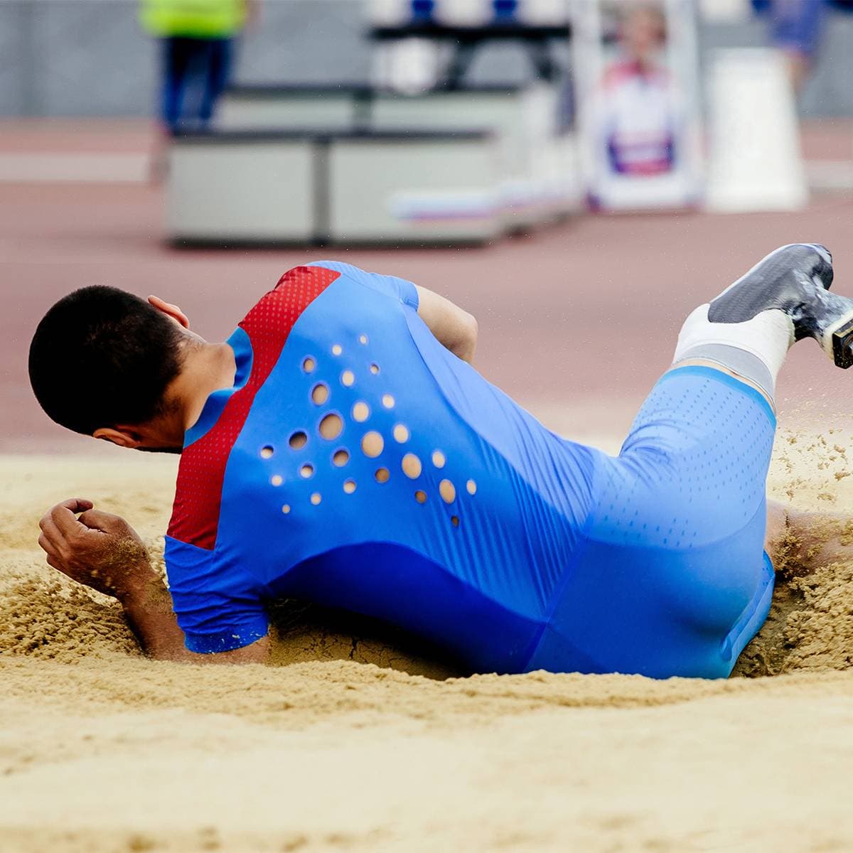 En friidrottare som hoppat längdhopp och precis landat i sanden.