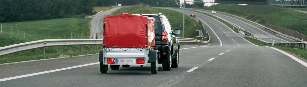 En bil drar en släpvagn på en väg