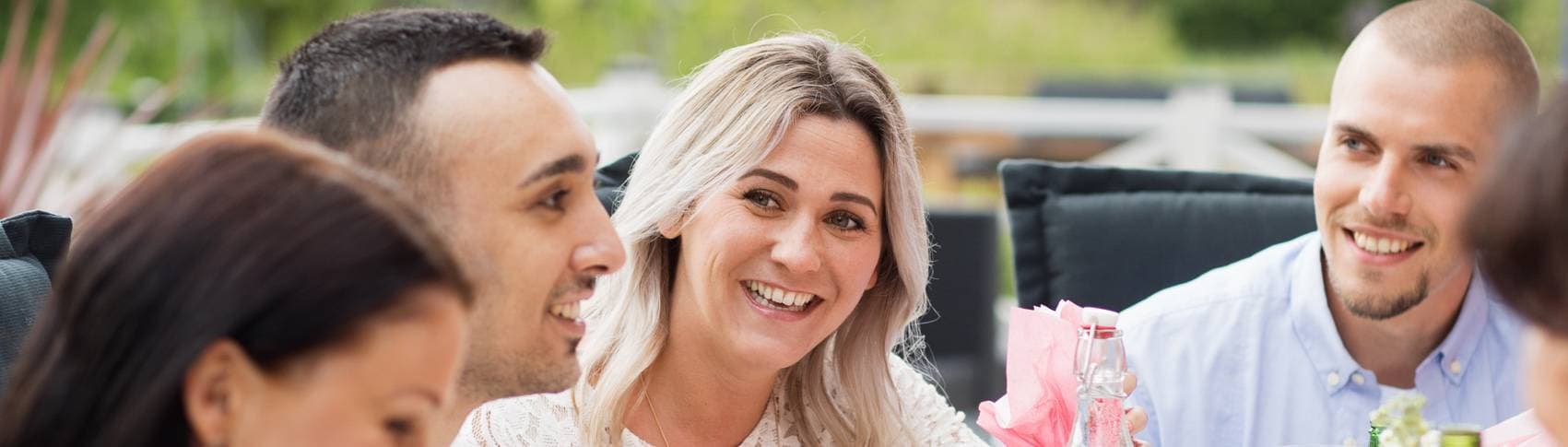 Bild: Glada människor som sitter runt ett matbord utomhus