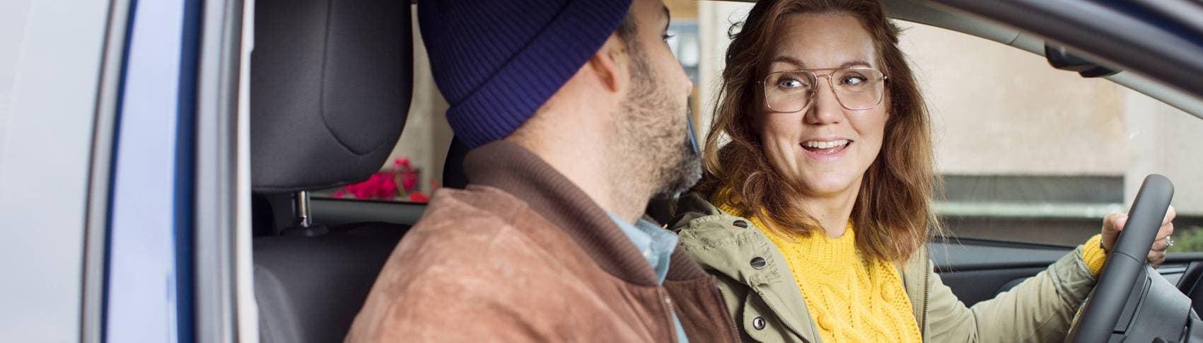 En kvinna och en man sitter och pratar i en bil.