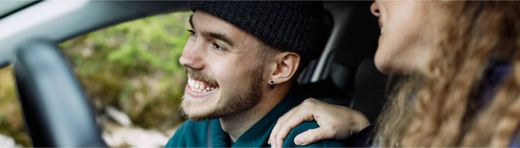 Ung kille sitter i bil och ser glad ut