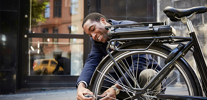 En man hukar sig och låser fast en cykel utomhus.