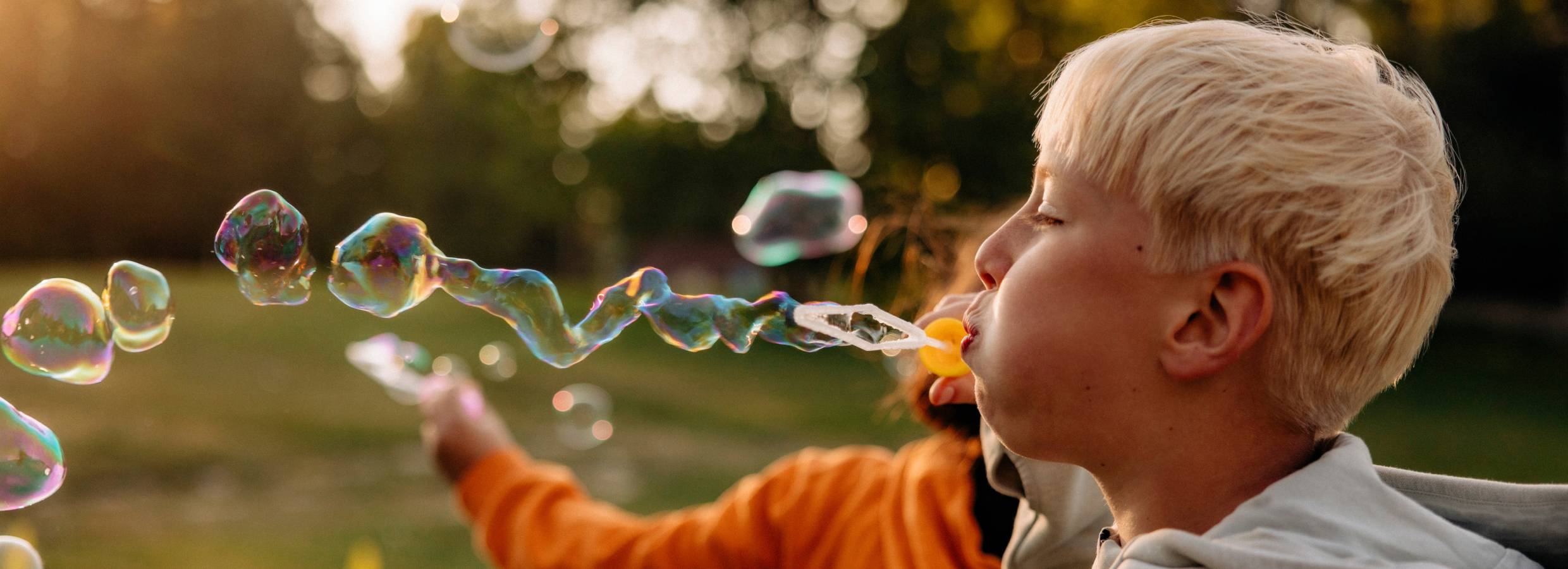 En pojke i profil blåser såpbubblor