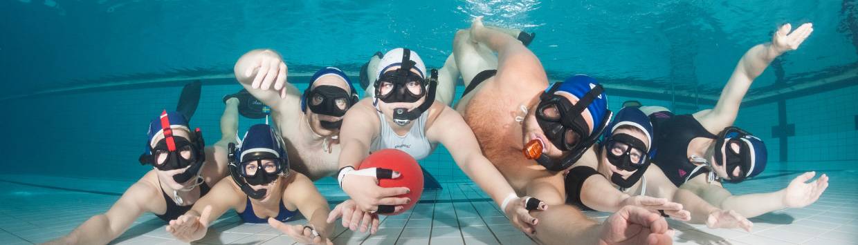 Sju dykare som poserar under vattnet i en pool